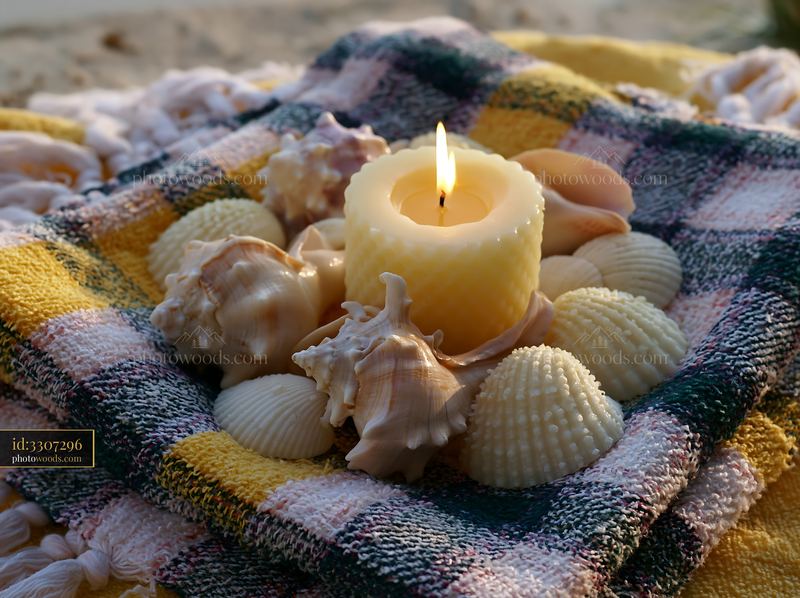 Candle surrounded by seashells on a textured cloth
