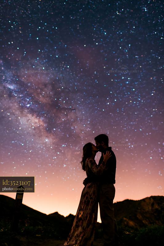 Young couple sharing a kiss underneath the Milky Way sky