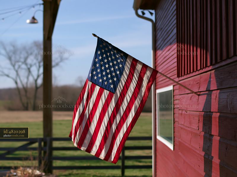 American flag waving in gentle breeze by a red barn