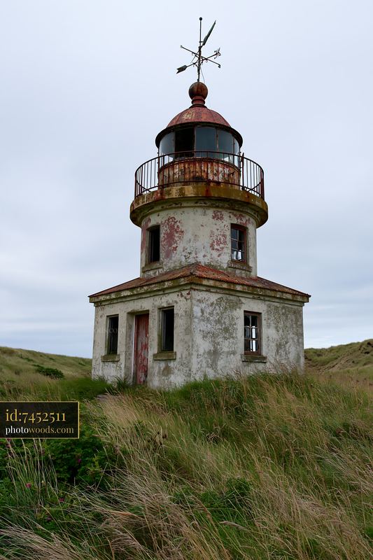 Abandoned lighthouse on a remote coast surrounded by tall grass