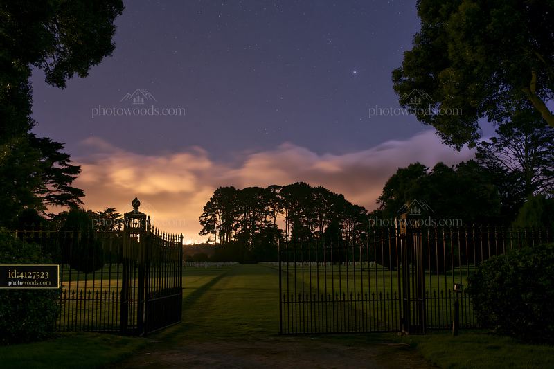 American cemetery under low clouds with stars in the night sky