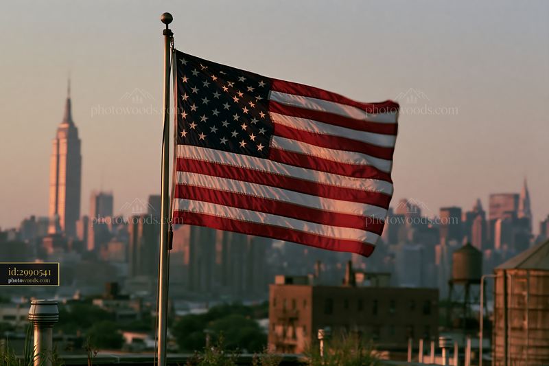 American flag flying in strong wind against city skyline