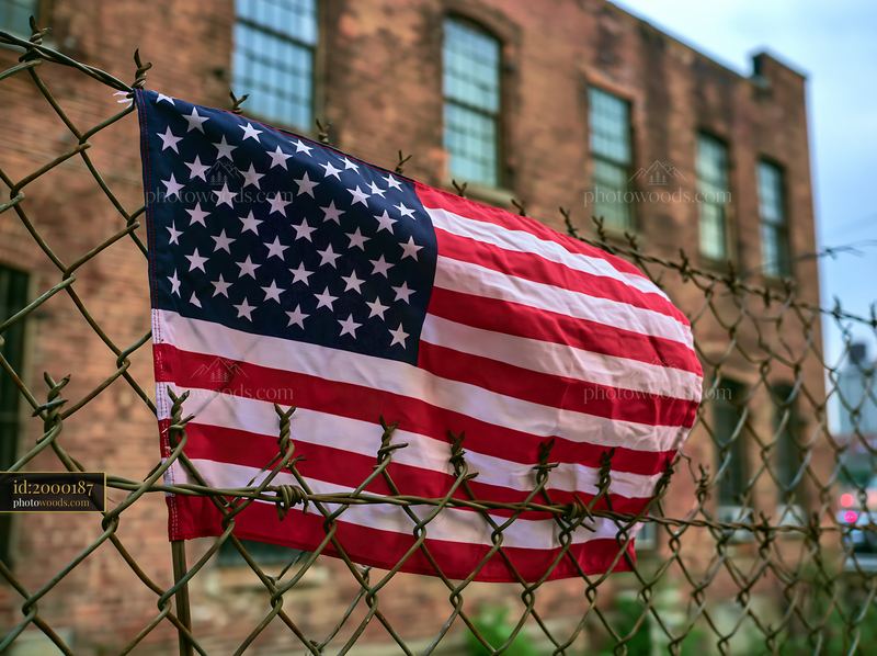 American flag behind barbed wire near a brick building