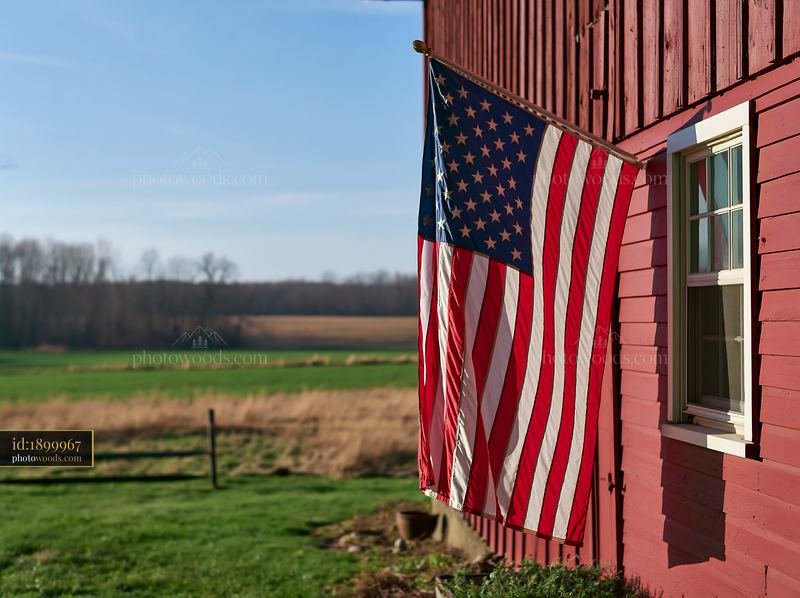 American flag waving in gentle breeze next to red barn