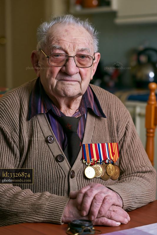 Veteran wearing medals with a proud expression in a home setting