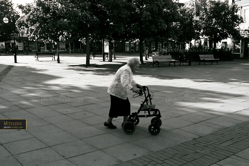 Elderly woman with Parkinson's disease walking outdoors in a square
