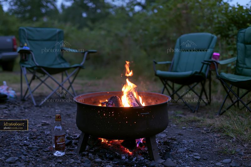 Empty bottle after party near campfire and chairs