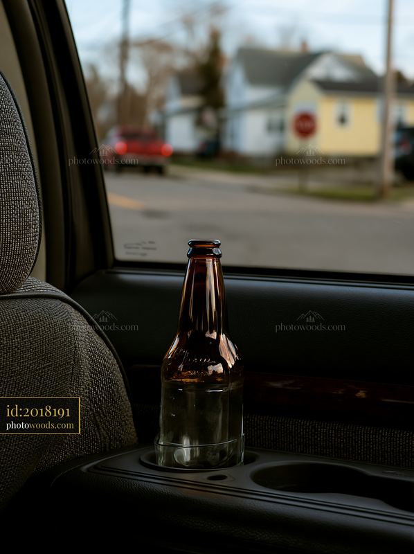 Empty bottle in car cup holder beside window view
