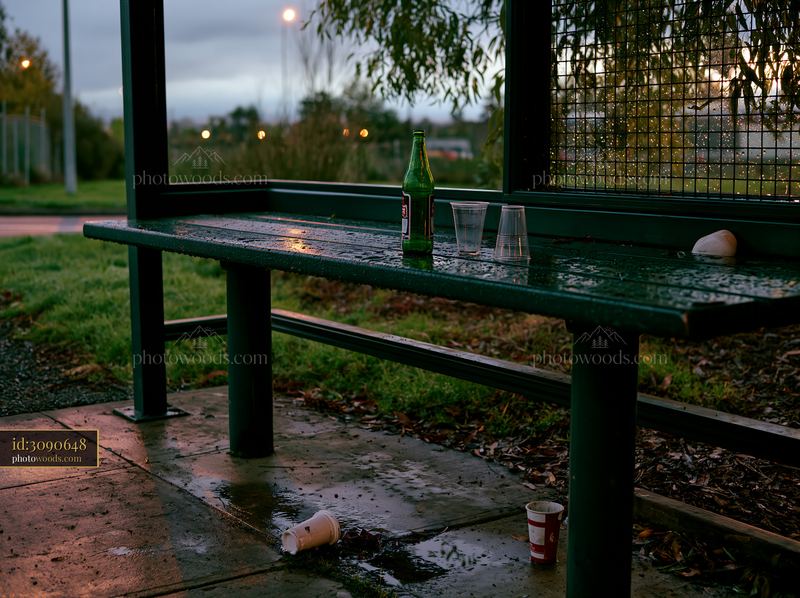 Empty bottle beside discarded cups at a bus stop