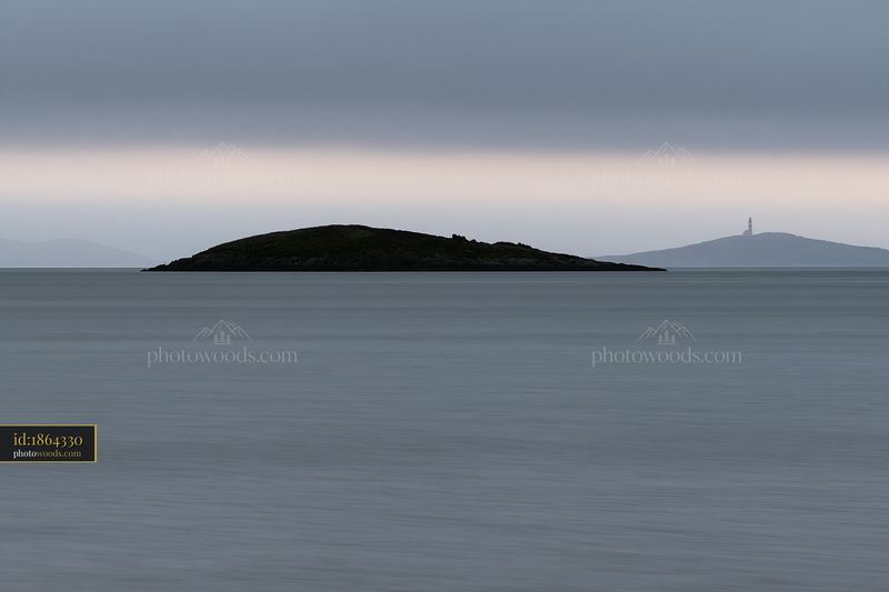Island with flowers in a calm bay under cloudy sky