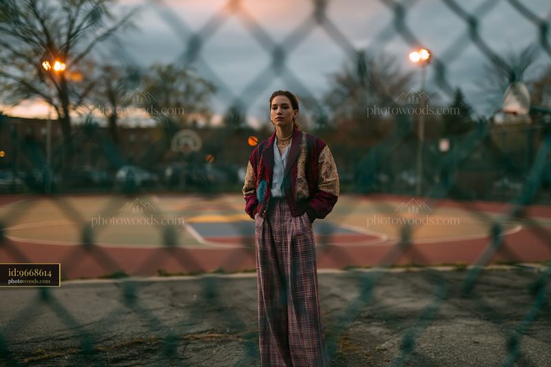Androgynous Model in Patchwork Outfit at Basketball Court Dusk