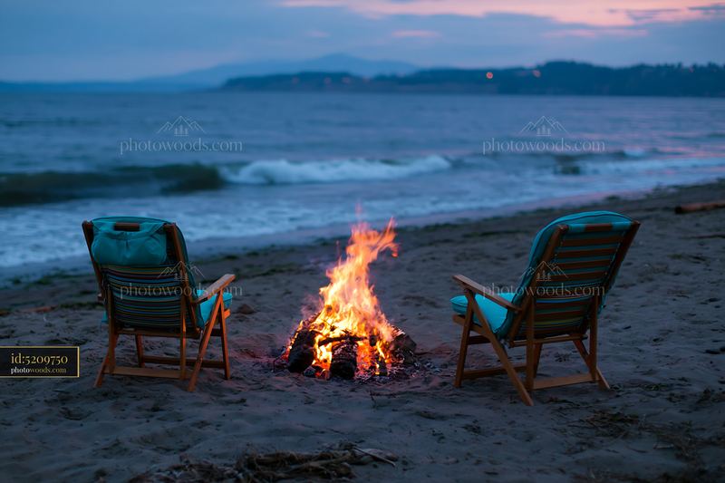 Beach bonfire with chairs beside a quiet coastline at dusk