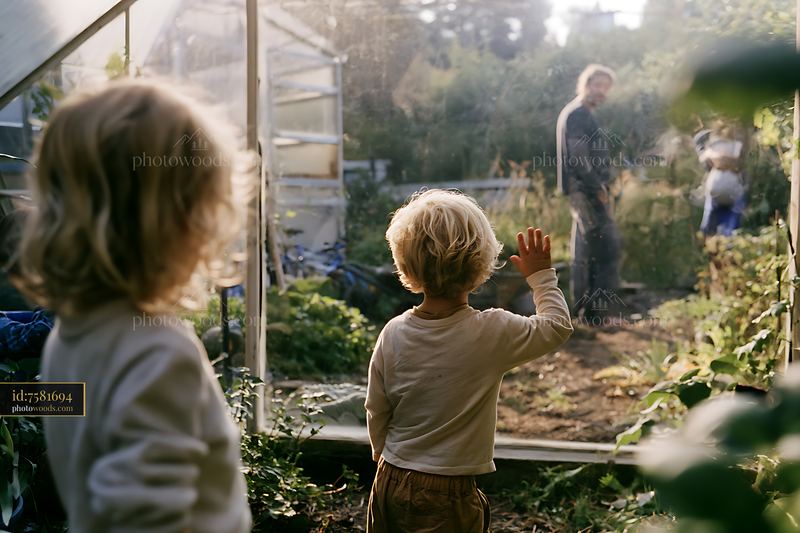 Blonde children waving from garden while parents stand nearby