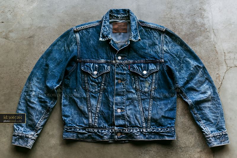Blue denim jacket with faded water marks on concrete