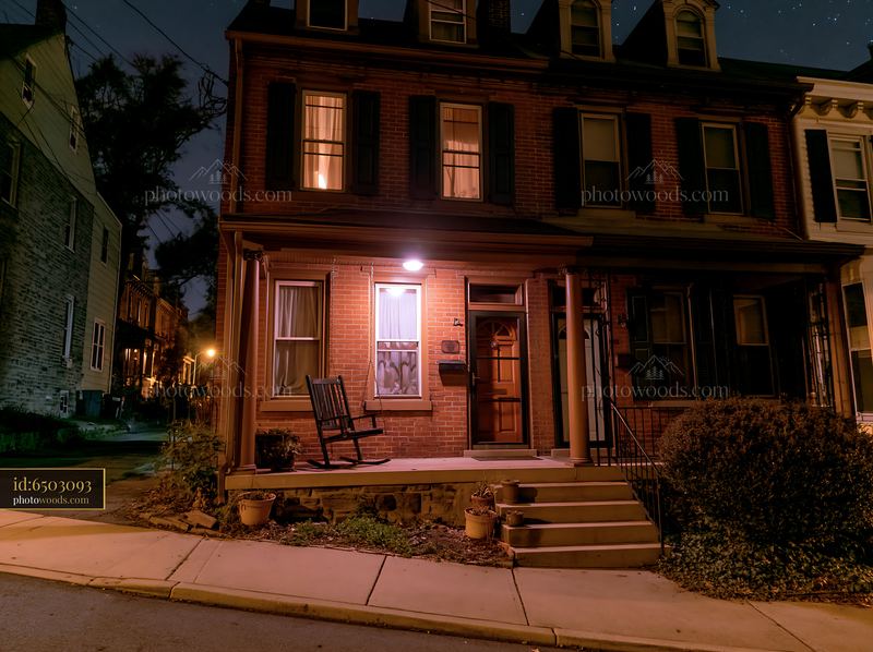 Brick row house with porch swing beneath a starry night sky