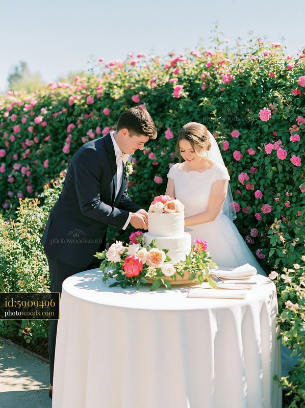 Bride and groom with wedding cake in a rose garden