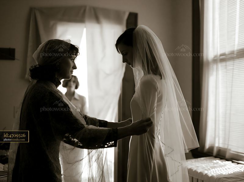 Bride and companion adjusting a wedding veil indoors
