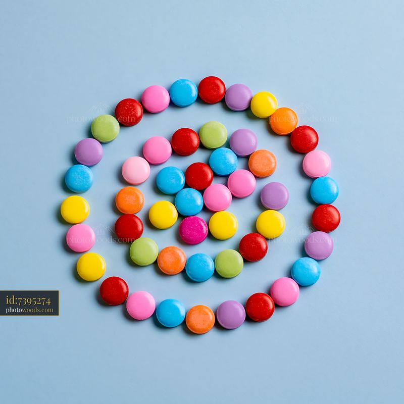 Colorful candy pieces forming spiral design on blue background