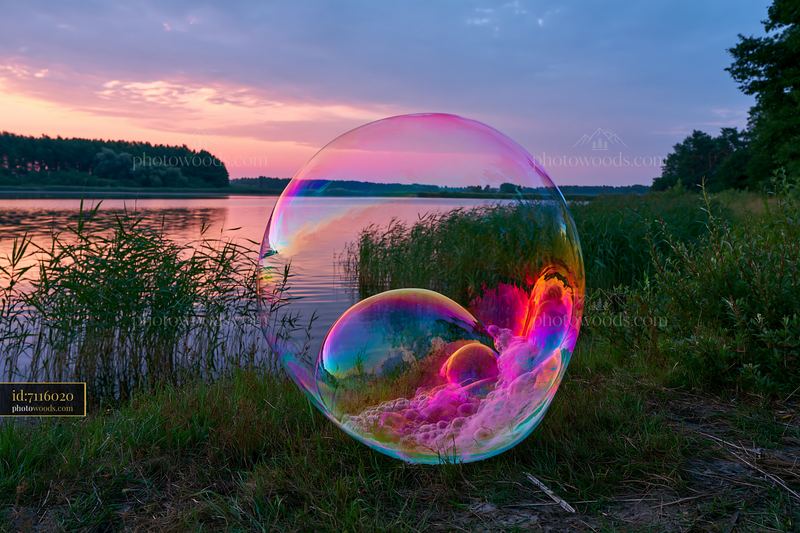 Colorful soap bubbles forming swirl by the water at sunset