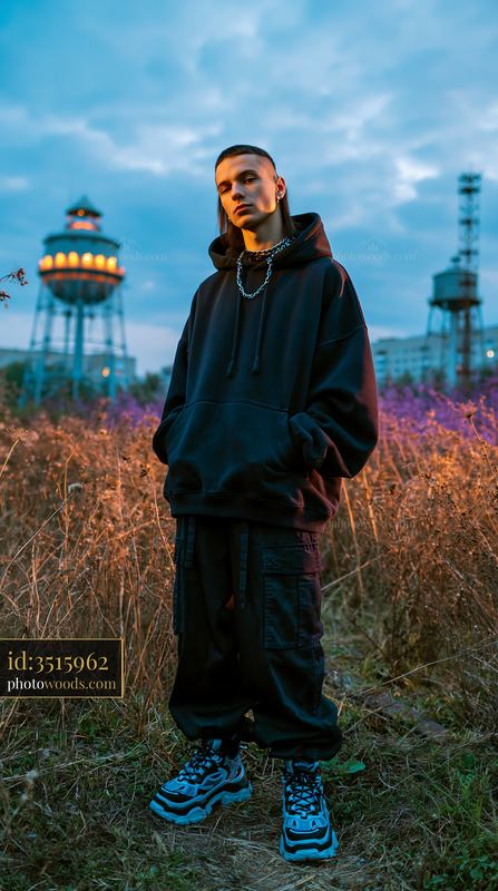 Confident Young Man in Oversized Hoodie by Water Tower