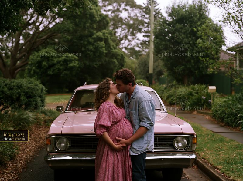 Couple kissing in front of a vintage car on a leafy driveway