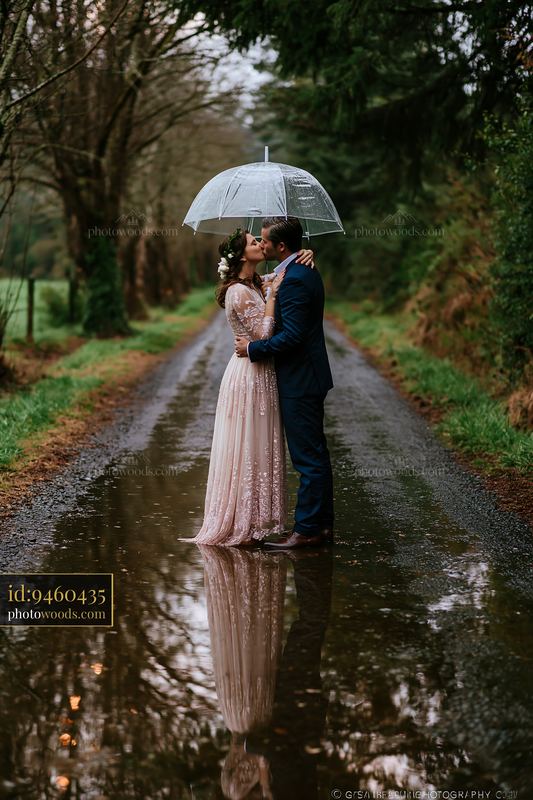 Couple kissing under umbrella on a rainy country road