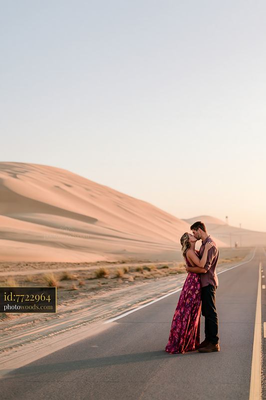Couple kissing on a desert road at sunset