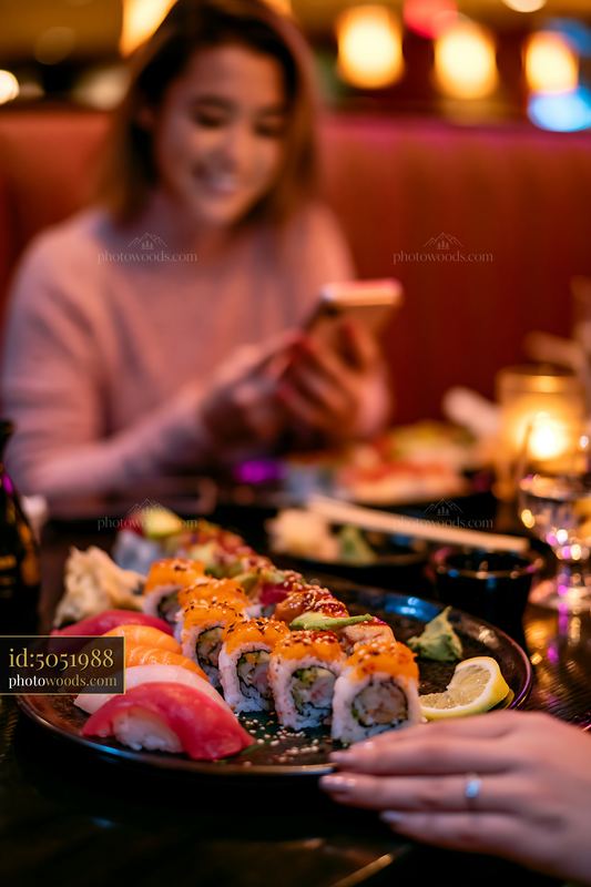 Sushi dinner under warm restaurant lighting with a person enjoying