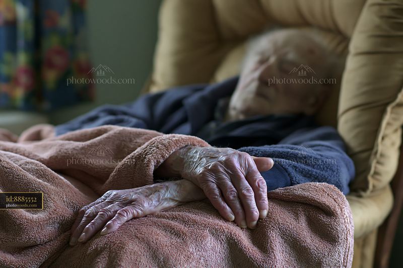 Elderly man with Alzheimer's resting with a blanket in a chair