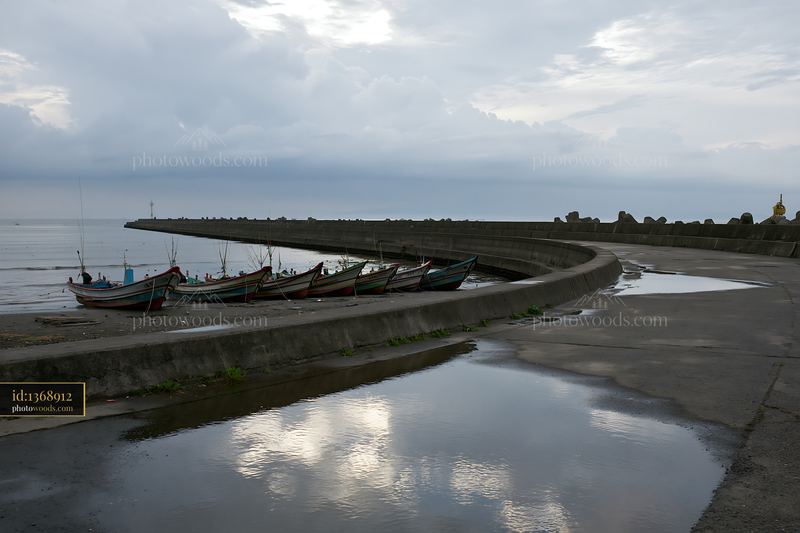 Coastline with protective sea wall and fishing boats at shore