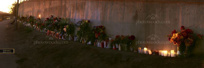 Flowers and candles at a memorial site under a sunset sky