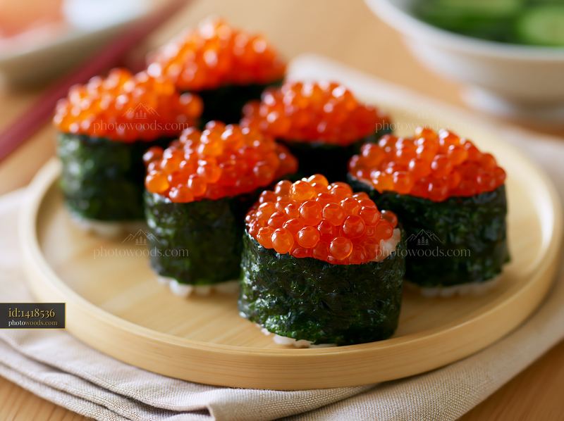 Close up view of ikura salmon roe sushi served on a wooden plate