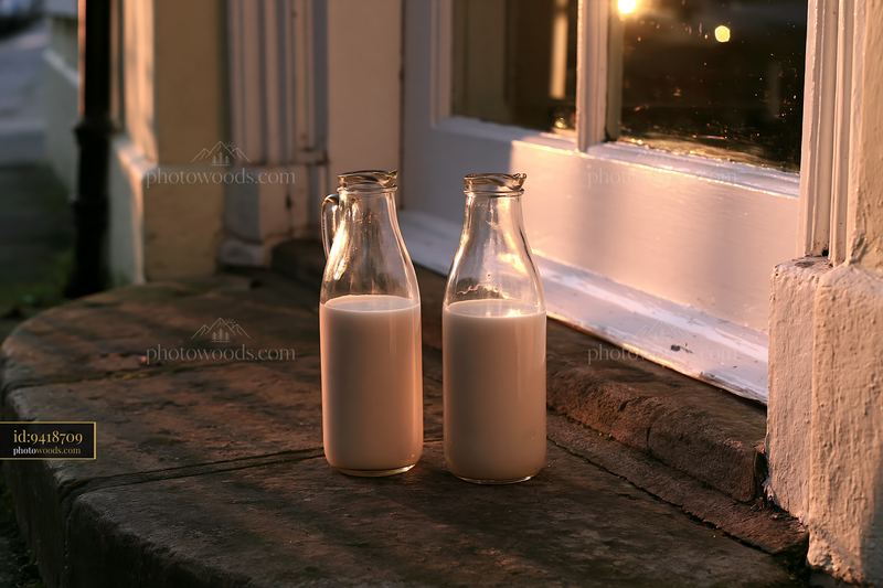 Glass milk bottles on a doorstep at sunrise