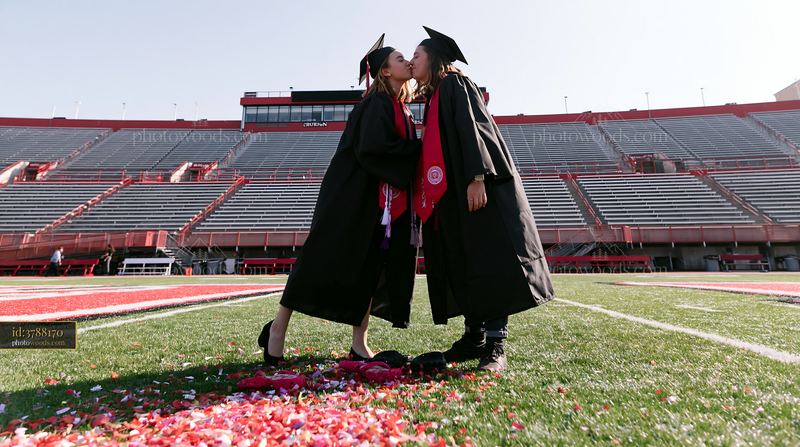 Graduates kissing on the field during celebration with confetti