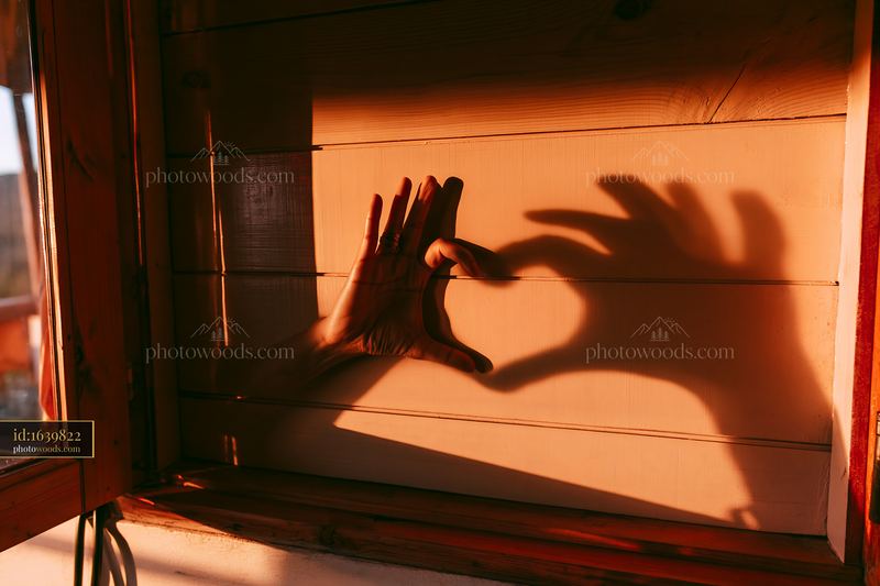 Heart shaped shadow from hands on wall near a window