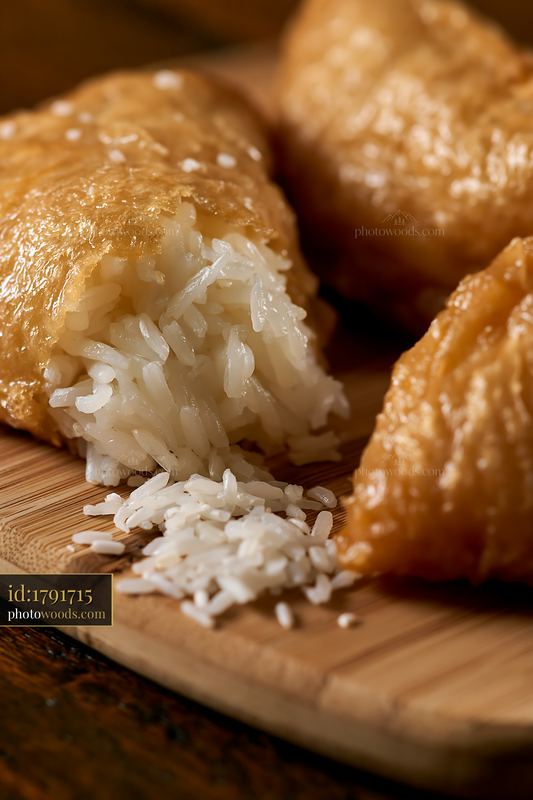Inari sushi pockets filled with rice on wooden board