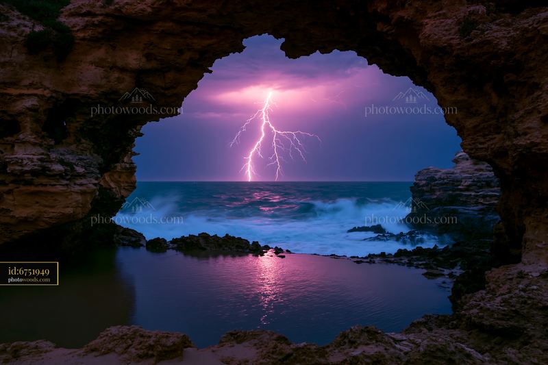 Lightning over Ocean Framed by a Rocky Coastal Cave