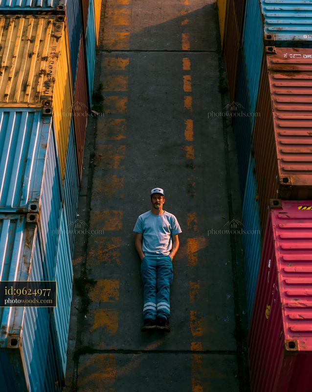 Man Lying on the Ground Surrounded by Colorful Shipping Containers