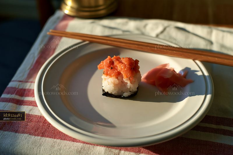 Single sushi piece with pickled ginger on a plate