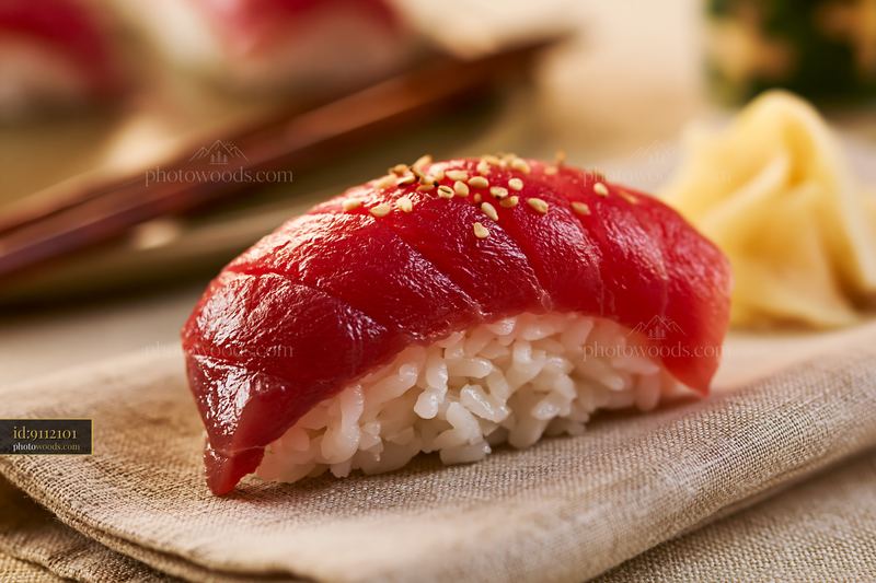 One sushi piece with pickled ginger on a cloth napkin