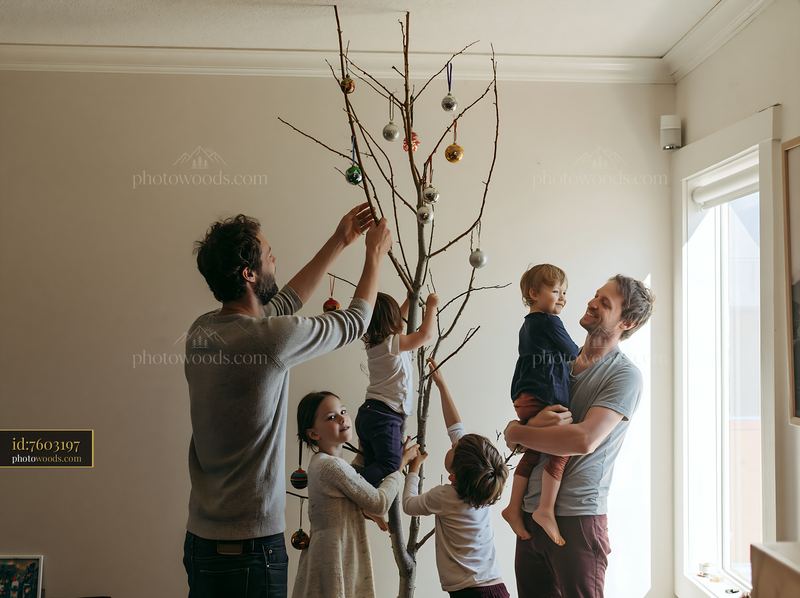 Parents and children decorating a branch Christmas tree