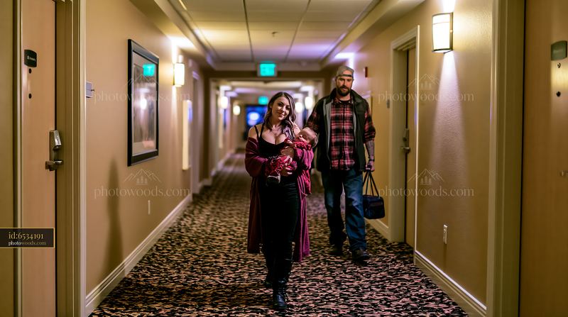 Parents carrying a sleeping child through a hotel hallway