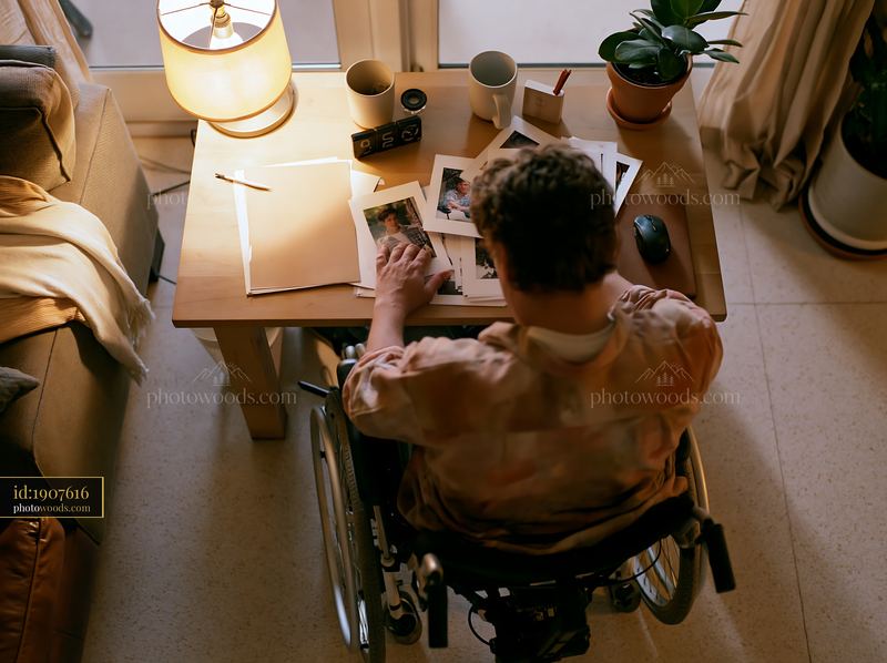 Person in wheelchair looking through photographs at home
