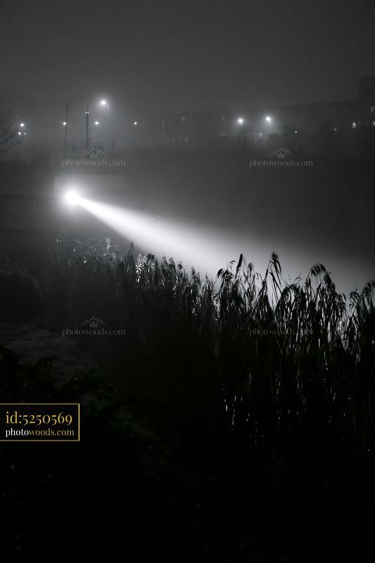 Police searchlights illuminate a foggy night scene