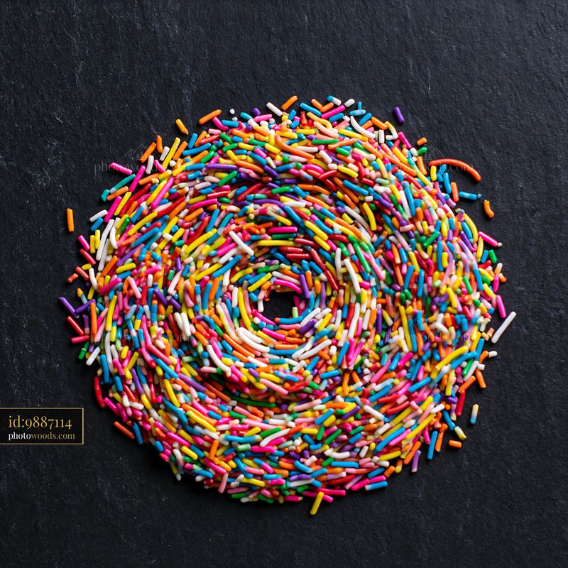 Rainbow sprinkles arranged in a swirl on a dark surface