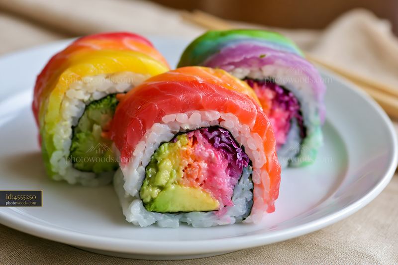Rainbow sushi roll close-up on a white plate with chopsticks