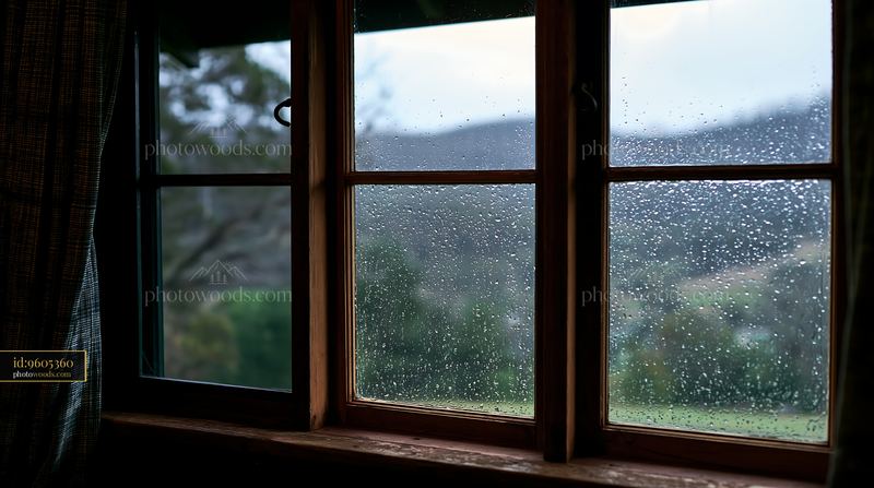 Raindrops on timber window with blurred hills in the background