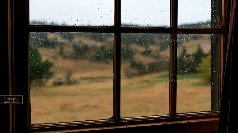Raindrops on timber window with blurred hills in background