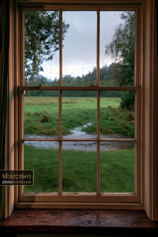 Rain on small cottage window overlooking field