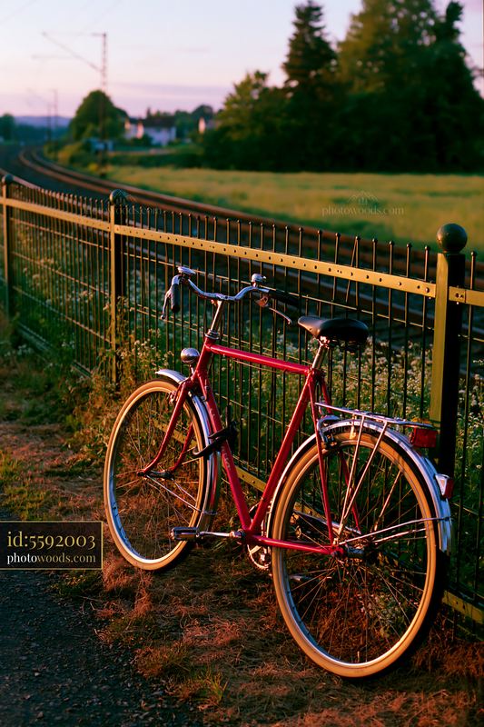 Red bicycle beside railway tracks at sunset